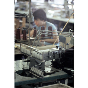 A garment worker works at a sewing machine in a clothing factory