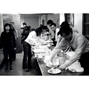 People line up at a buffet table in Association headquarters during Thanksgiving dinner