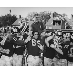 The football team hoists coach Joe Zabilski onto their shoulders after a game to celebrate his retirement