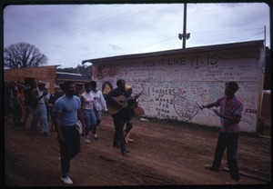 Guitarists leads a line of residents past a graffiti-covered wall in the Resurrection City encampment