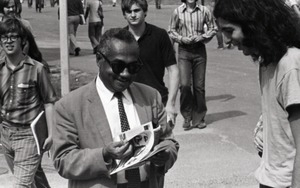 Bill Grabin showing Free Spirit Press magazine to African American faculty member in front of the UMass Amherst Student Union