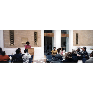 Audience members listen to a woman speak at a town hall meeting