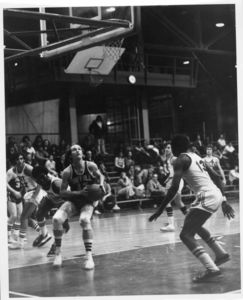 Suffolk University men's basketball player taking shot, 1975