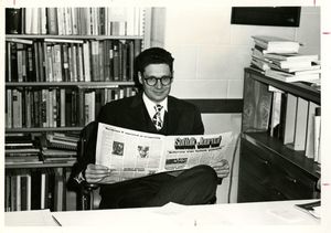 Suffolk University Dean Donald Grunewald (CAS), seated and holding a copy of Suffolk Journal