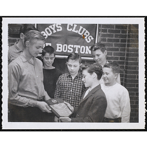 A young man presents a plaque to a boy while five others look on at a Boys' Clubs of Boston awards event
