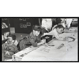 Two girls with painted faces drawing on a large sheet of paper at a joint Charlestown Boys & Girls Club and Charlestown Against Drugs (CHAD) event