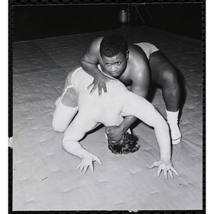 A wrestler holds down his opponent on a mat in the South Boston gymnasium