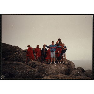 A boy stands in front of a group of youth at the top of the White Mountains