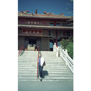 Chinese Progressive Association member stands in front of a building built in a Chinese style