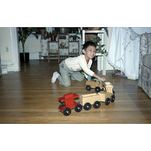 Young boy plays with a wooden train toy