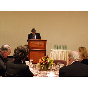 Harry P. Keegan III (CBA '64), left, and Neal Finnegan (CBA '61), second from the right, listen to Dr. Ira R. Weiss, Dean of the College of Business Administration, speaking from the podium