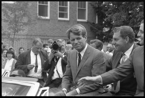 Robert F. Kennedy (left) seated in an open car at the Turkey Day parade, while stumping for Democratic candidates in the northern Midwest