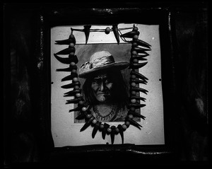 Bear tooth necklace laid on framed sketch of Geronimo