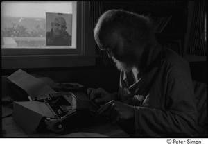 Ram Dass at typewriter: Ram Dass typing, with a portrait of Neem Karoli Baba in the background