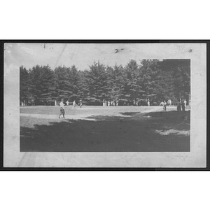 View of baseball field surrounded by trees while people play