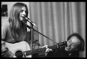 Judy Collins with guitar at the microphone, accompanied by Michael Sahl on piano