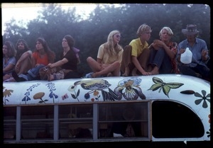 Concert goers seated atop a painted bus, Woodstock Festival