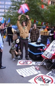Occupy Wall Street: demonstrator in a Guy Fawkes mask next to a demonstrator raising American and Puerto Rican flags