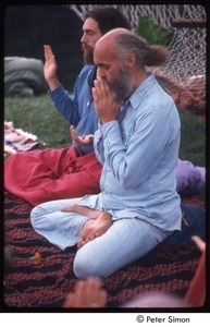 Ram Dass teaching in a half lotus with Krishna Das on his right