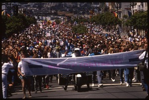 Massive crowd marching in the San Francisco Pride Parade, carrying banner reading 'Mayors contingent': Art Agnos waving to the crowd from the back of an automobile