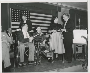 Unidentified man handing a scroll to a woman with forearm crutches at an ICD event