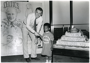 Mayor Raymond L. Flynn next to Boston Celtics cake with unidentified small boy wearing "Official City Greeter" t-shirt