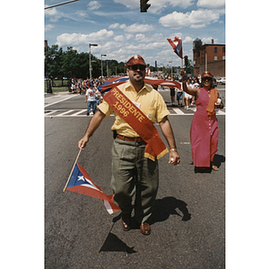 A man wears a Presidente 1996 sash while walking with the Festival Puertorriqueño parade