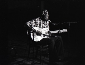 Taj Mahal in concert at Northfield, Mass.: Taj Mahal seated, playing steel guitar