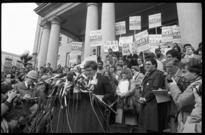 Gary Hart at a microphone-encrusted podium, addressing an crowd after renewing his bid for the Democratic nomination for the presidency