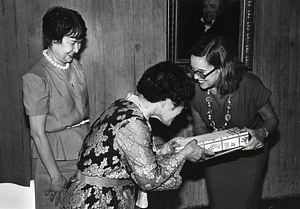 Katharine D. Kane receiving a gift from two unidentified Asian women