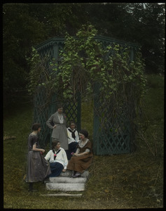 Young women sitting on steps by grape arbor