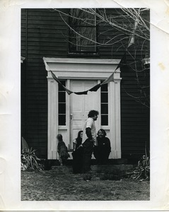 Cathy Rogers, Ira Krasnik, and Michael Curry seated with a dog by the front door, Montague Farm Commune