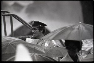 Policeman looking over umbrellas, awaiting the arrival of Gerald Ford to dedicate the Old Great Falls Historic District as a national historic landmark