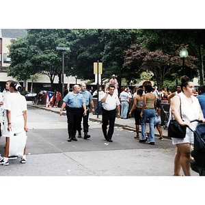 Three policemen stroll down the street past festival goers at Festival Betances.