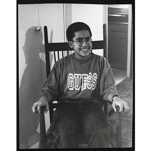 A boy smiling for the camera while sitting in a chair
