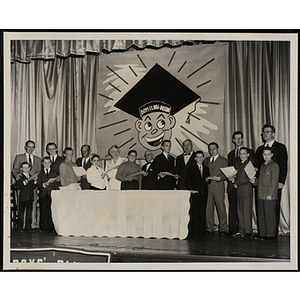 Adults and boys pose with certificates on a stage during a Father and Son's Banquet