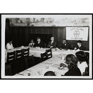 Adults and boys sit at adjoining tables during a Mothers' Club event