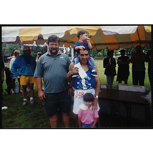 A man with two children poses with another man during the Battle of Bunker Hill Road Race