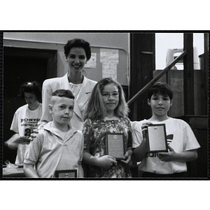 Heather Khan, a former news anchor, posing with two boys and a girl holding their awards at a Kiwanis Awards Night