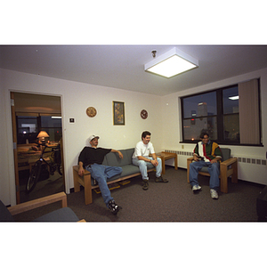 Three students sit in the common area of their residence hall suite