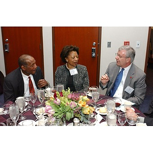 Three seated guests converse at The National Council Dinner