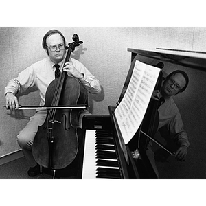 Associate Professor of Biology, Charles Ellis, plays the cello in front of a piano