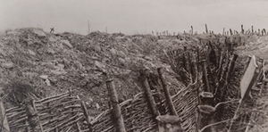 Ground-level view of a trench with barbed wire and a small cross visible on the horizon, Fort Douaumont