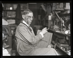 Walter G. Wolfe, industrial lens maker, seated at his work bench