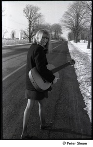 Karen Helberg walking down a snowy road with her acoustic guitar