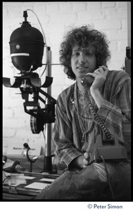 Peter Simon seated in a darkroom next to an enlarger, talking on the telephone