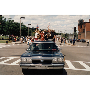 A car pulls a parade float filled with people during the Festival Puertorriqueño