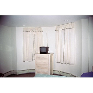 A television and a dresser in a bay window.