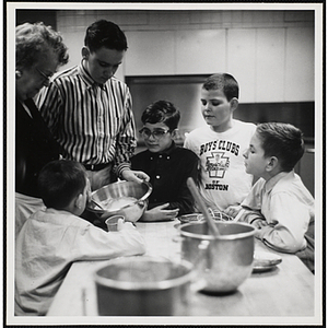 Members of the Tom Pappas Chefs' Club prepare ingredients in a kitchen with an unidentified woman