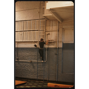 A boy climbs a ladder next to a shelf at the Charlestown gymnasium